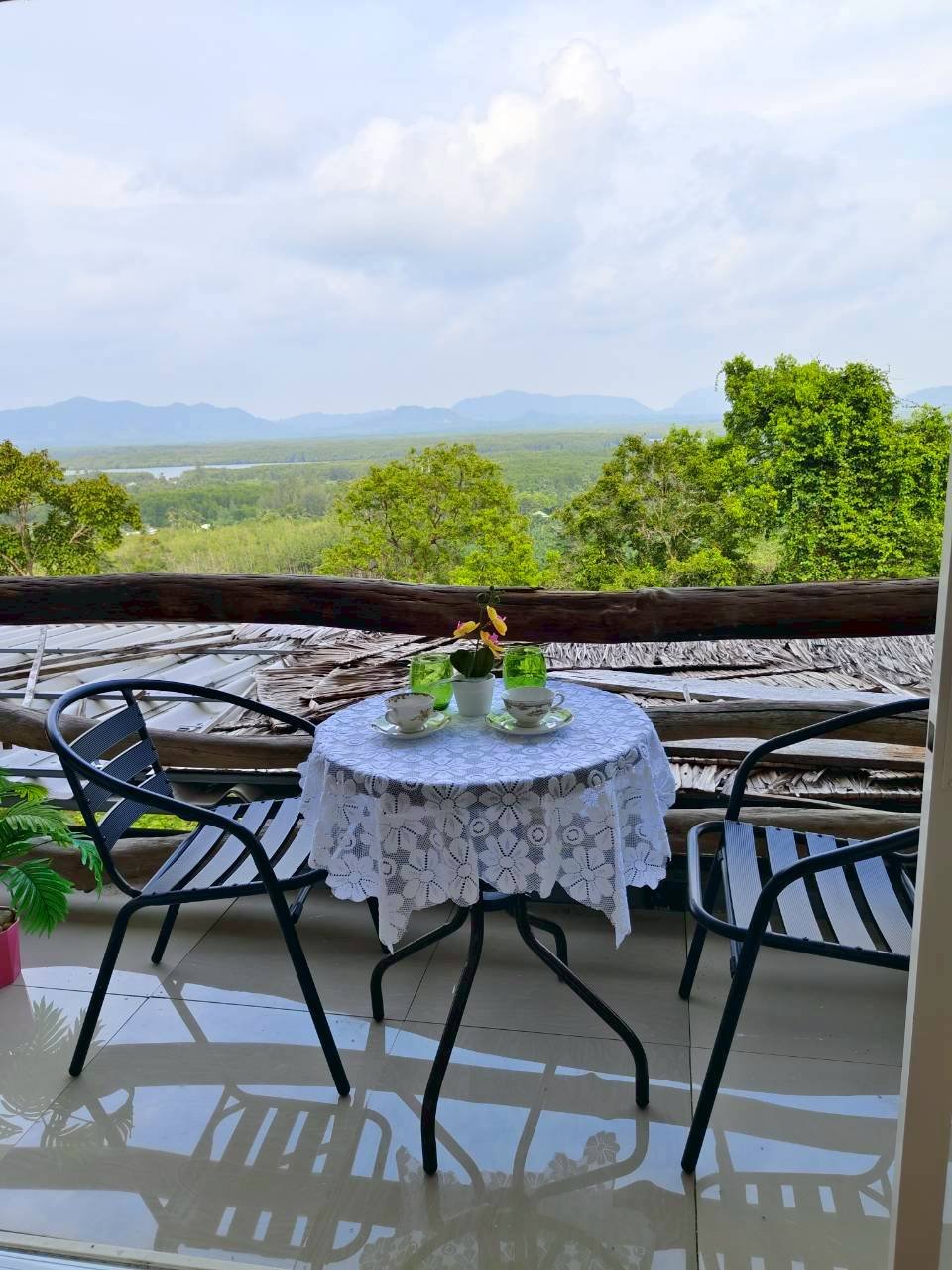Balcony seating with a table and wide green mountain view